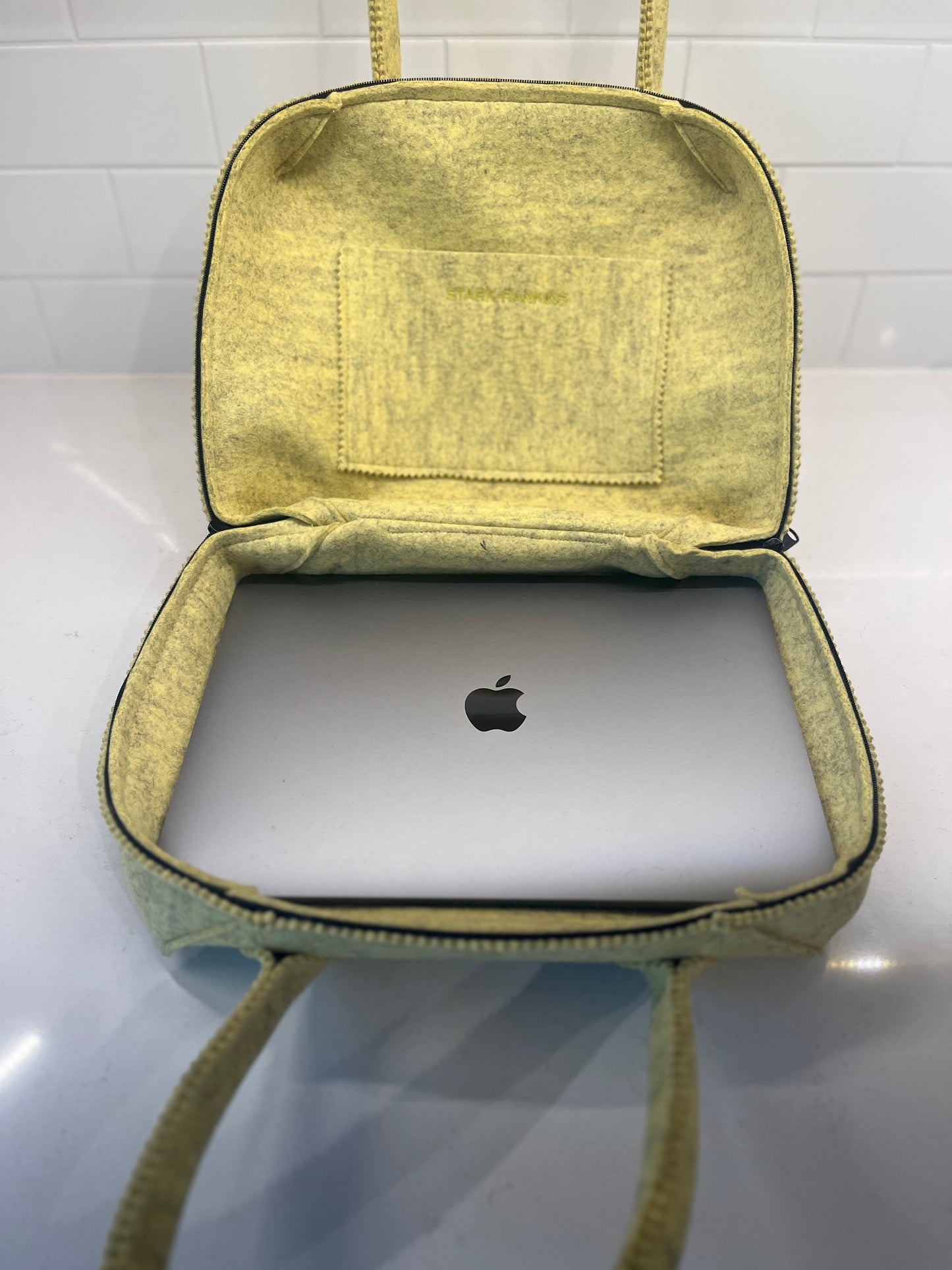 Open yellow bag with a closed silver laptop inside, displaying an apple logo.