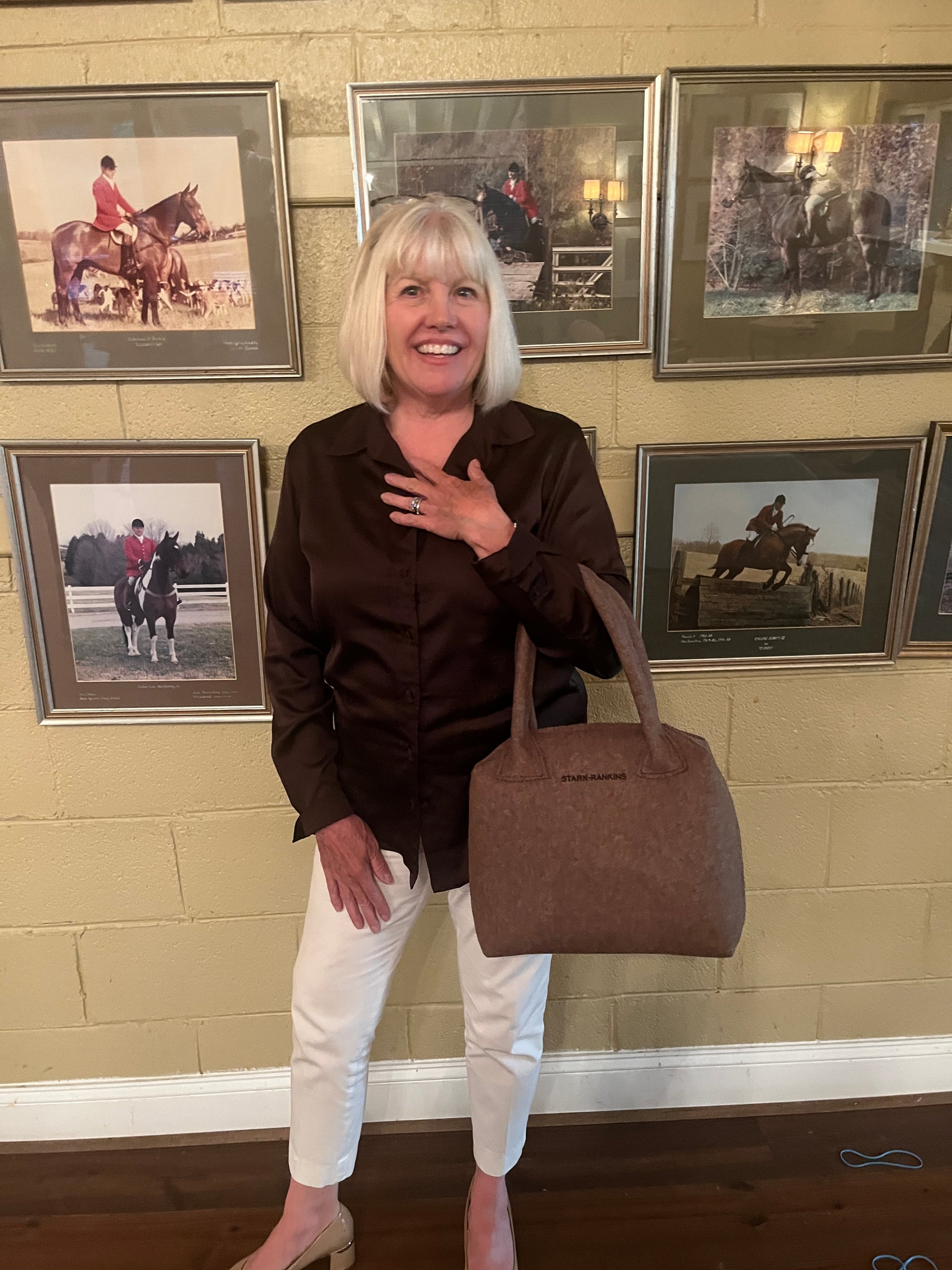 A handbag designer, holding a brown handbag.