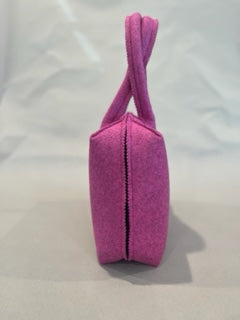 A side view of a pink felt handbag with a single strap, set against a plain background.