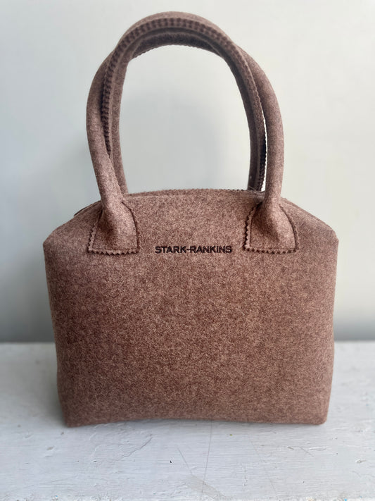 A brown felt handbag with sturdy handles is placed on a white surface. It features the text "STARK-RANKINS" on the front.