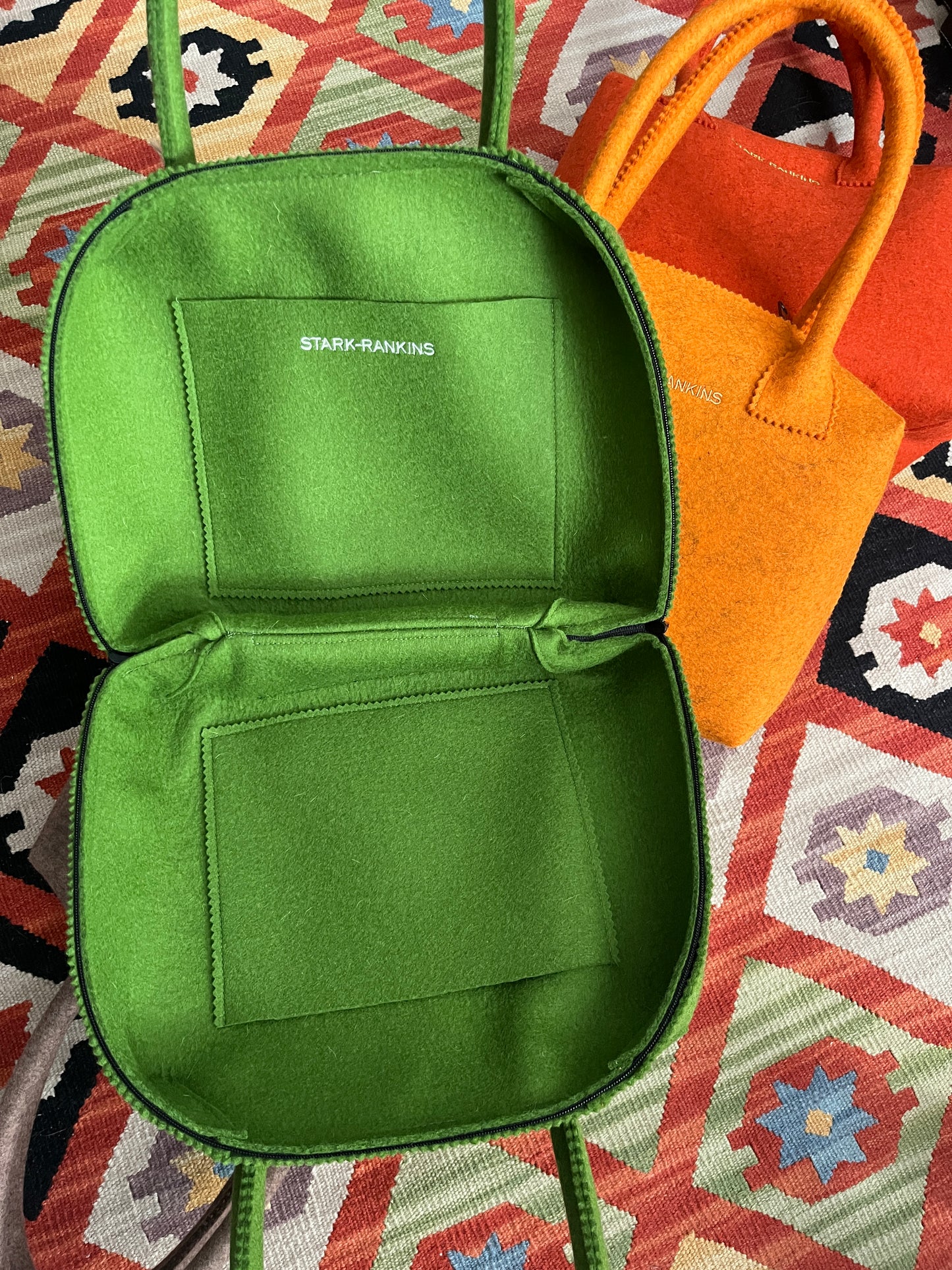 Two open bags on a patterned surface; one green with "Stark-Rankins" inside, the other orange.