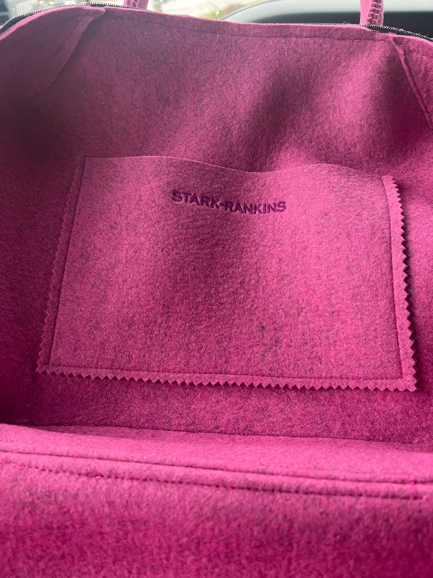 Close-up of an empty pink felt bag with a stitched pocket, featuring the text "STARK RANKINS".